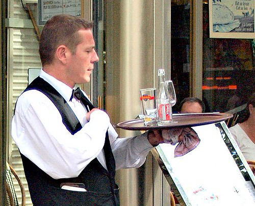 Un camarero sirviendo una mesa en un restaurante francés